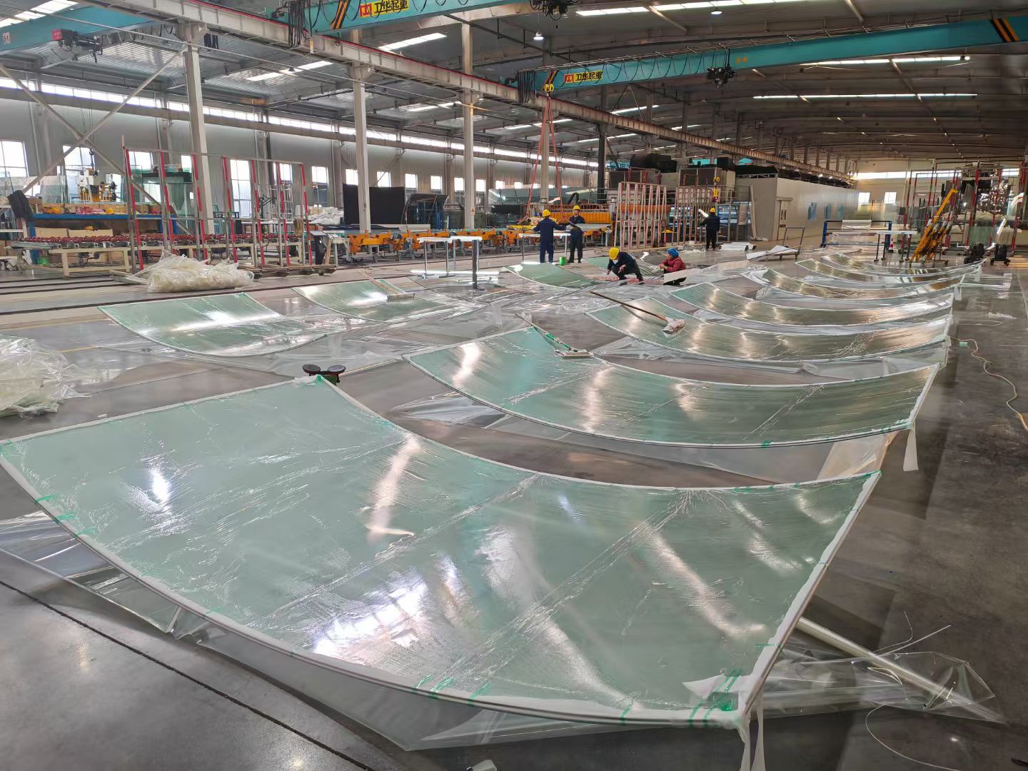 Rows of curved glass panels on the workshop floor.